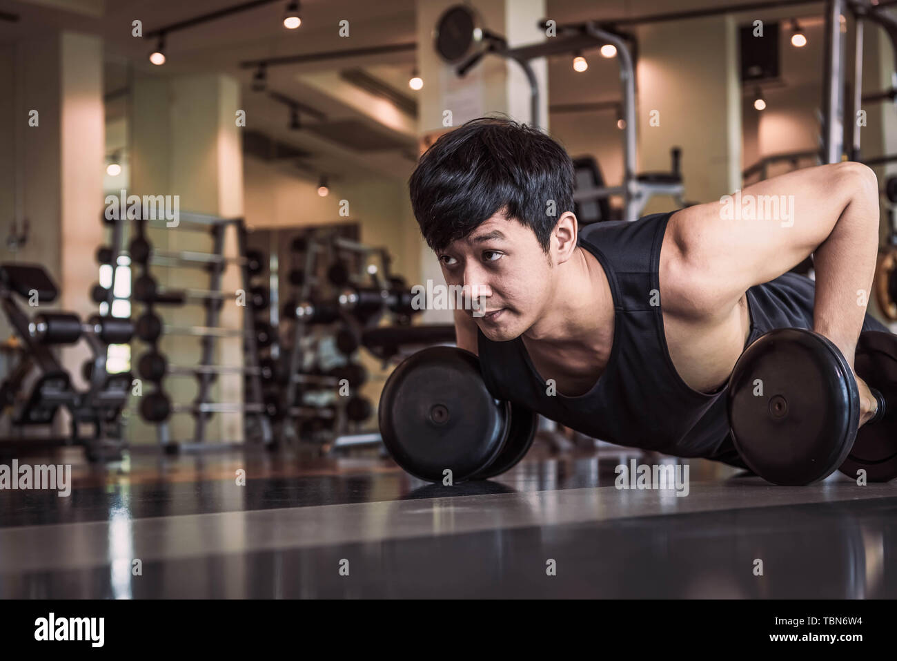 Portrait of Asian man doing fitness poussant l'exercice avec haltère dans une salle de sport. Les gens de vie et Sport concept. Sportsman holding poids par deux part Banque D'Images