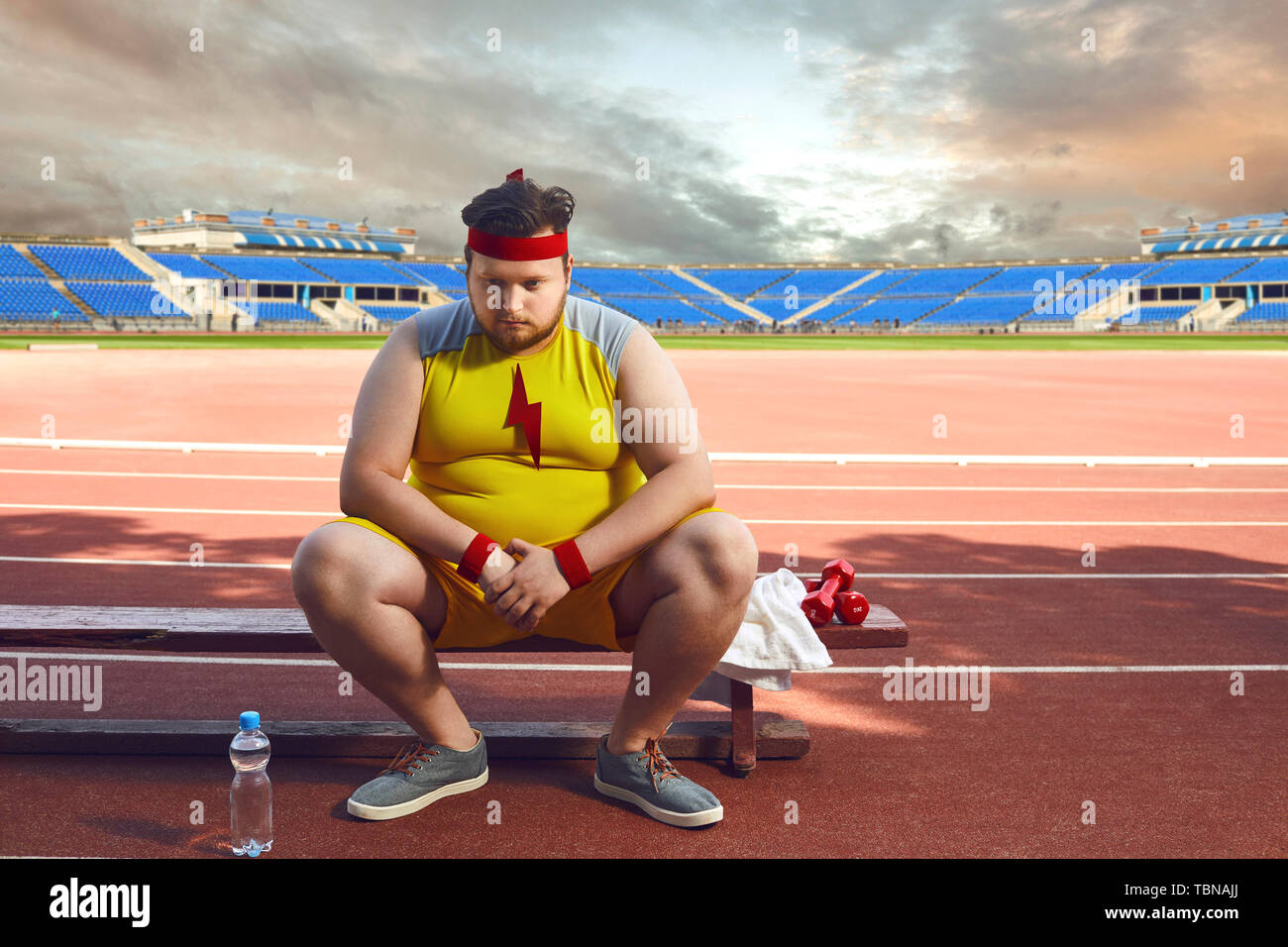 Triste gras homme assis dans le stade après la formation. Le concept de sport, la perte de poids, le régime alimentaire. Banque D'Images