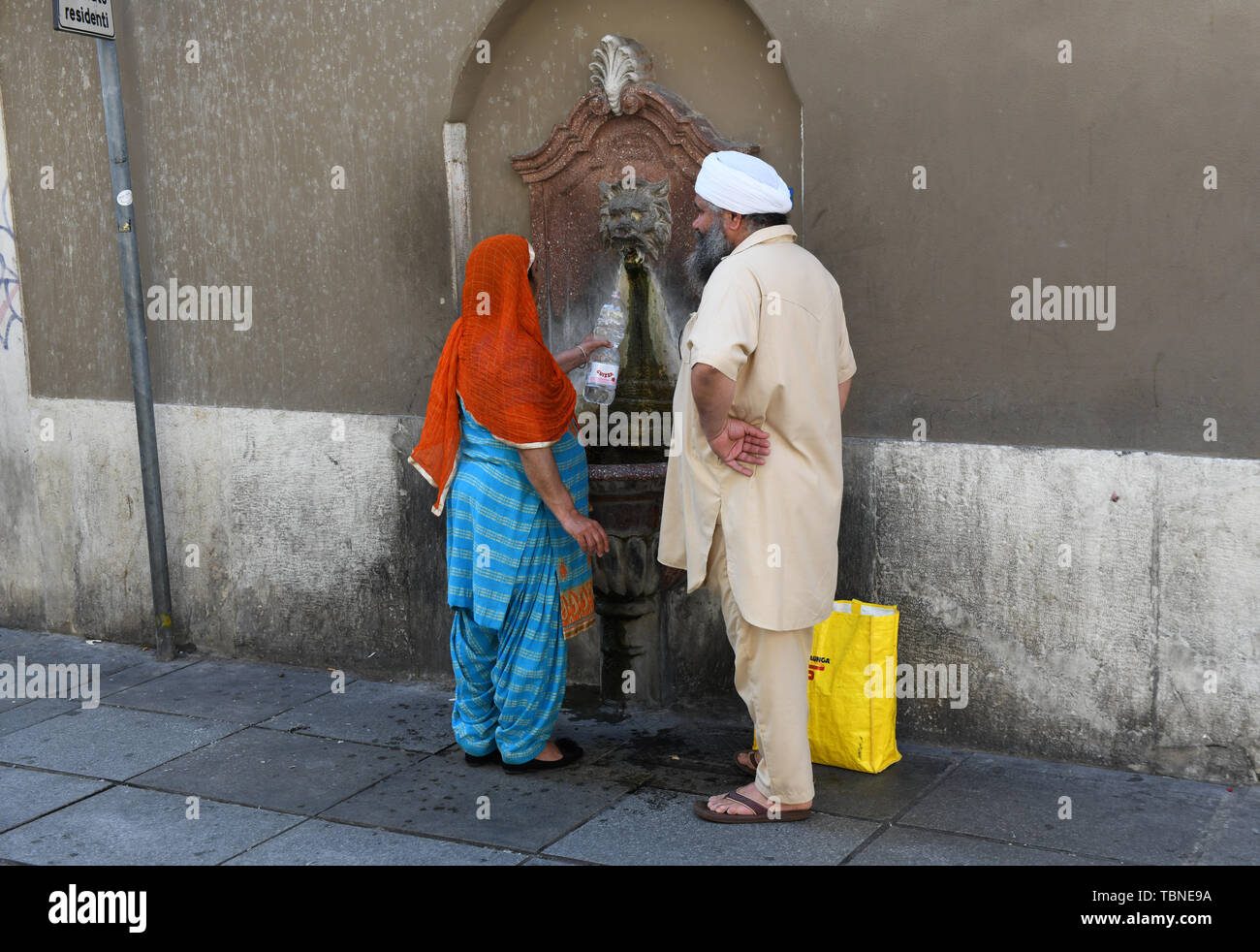 Asian couple remplir bouteille d'eau en plastique d'une fontaine d'eau publique à Brescia Italie Banque D'Images
