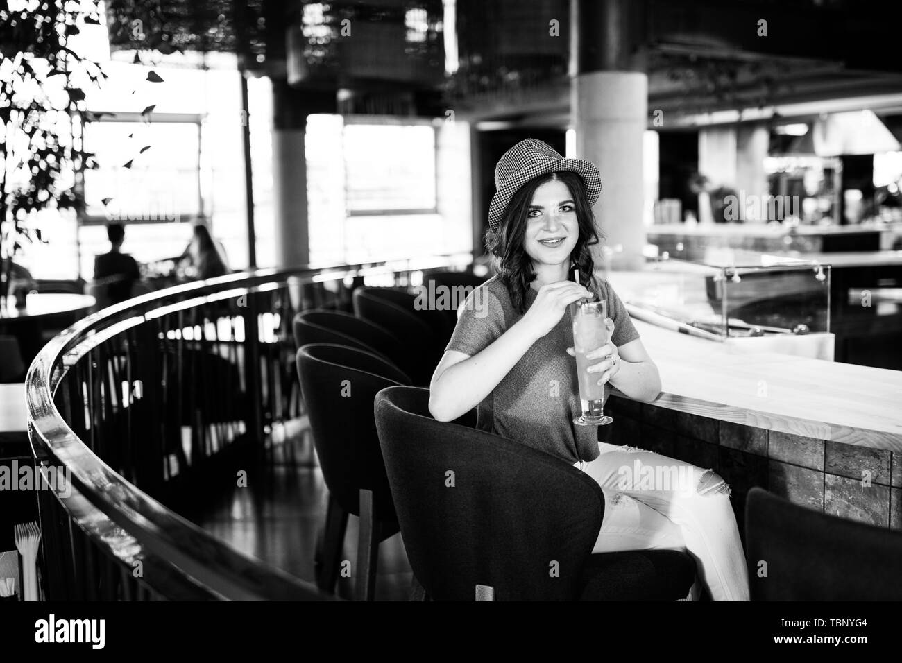 Très jolie brunette mignon assis dans un restaurant derrière un bar et de boire un cocktail Banque D'Images