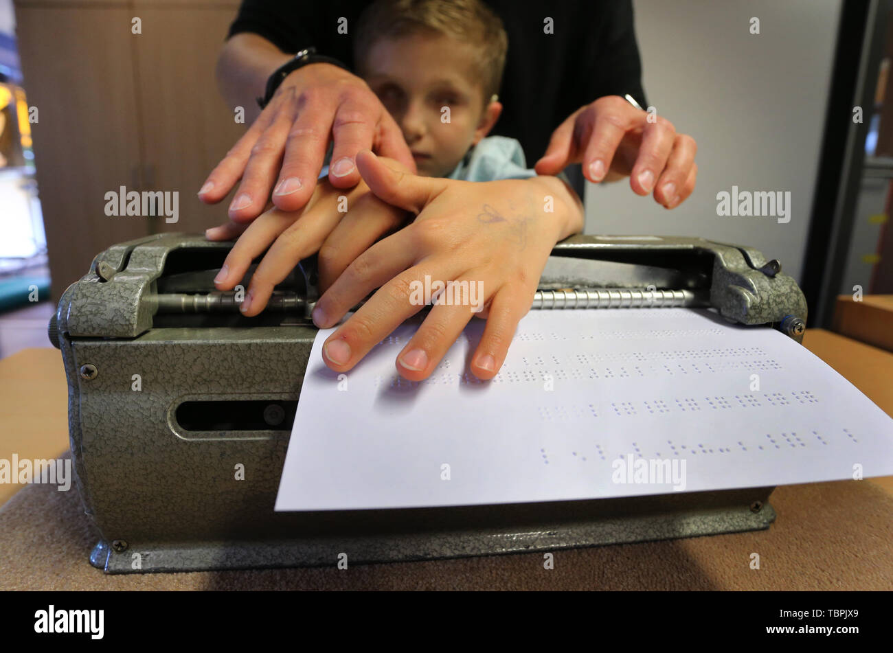 01 juin 2019, la Bavière, Würzburg : les sourds-aveugles Lucas, appuyé par son éducateur Stefanie Tröster, estime pour les lettres en braille qu'il a tapé dans une machine à écrire braille avant (dpa-KORR : 'Das Leben' erfühlen de 03.06.2019). Photo : Karl-Josef Opim/dpa Banque D'Images