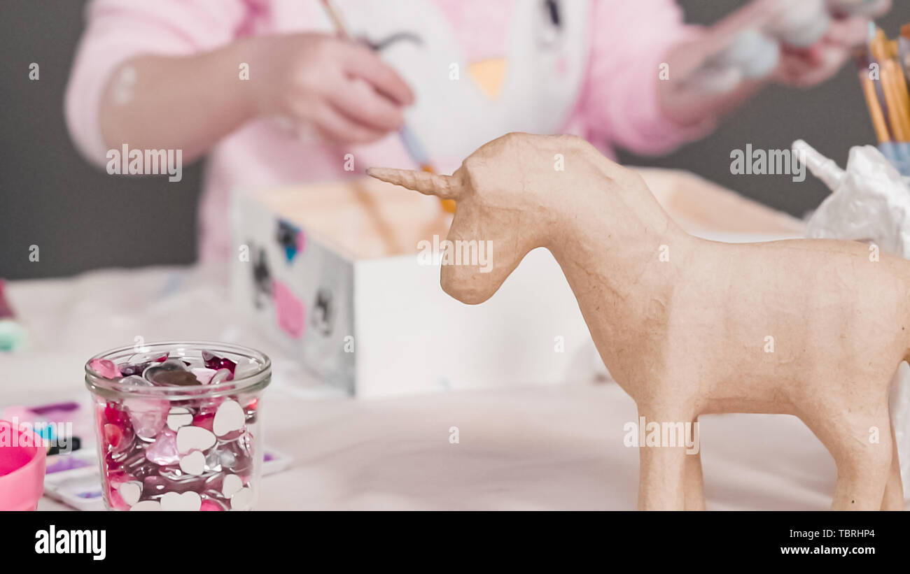 Peindre avec une peinture acrylique blanche licorne figurine en papier mâché. Banque D'Images