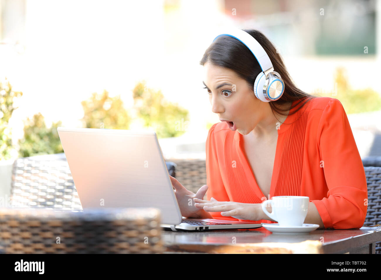 Femme choqué trouver media propose dans un ordinateur portable assis dans un café terrasse Banque D'Images