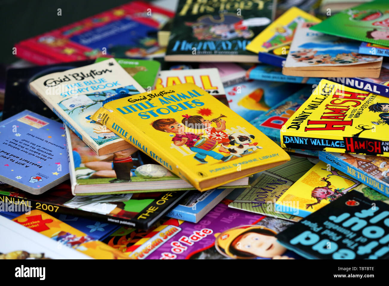 Pile de livres pour enfants en vente sur un étal de bienfaisance dans la région de Sussex, UK. Banque D'Images
