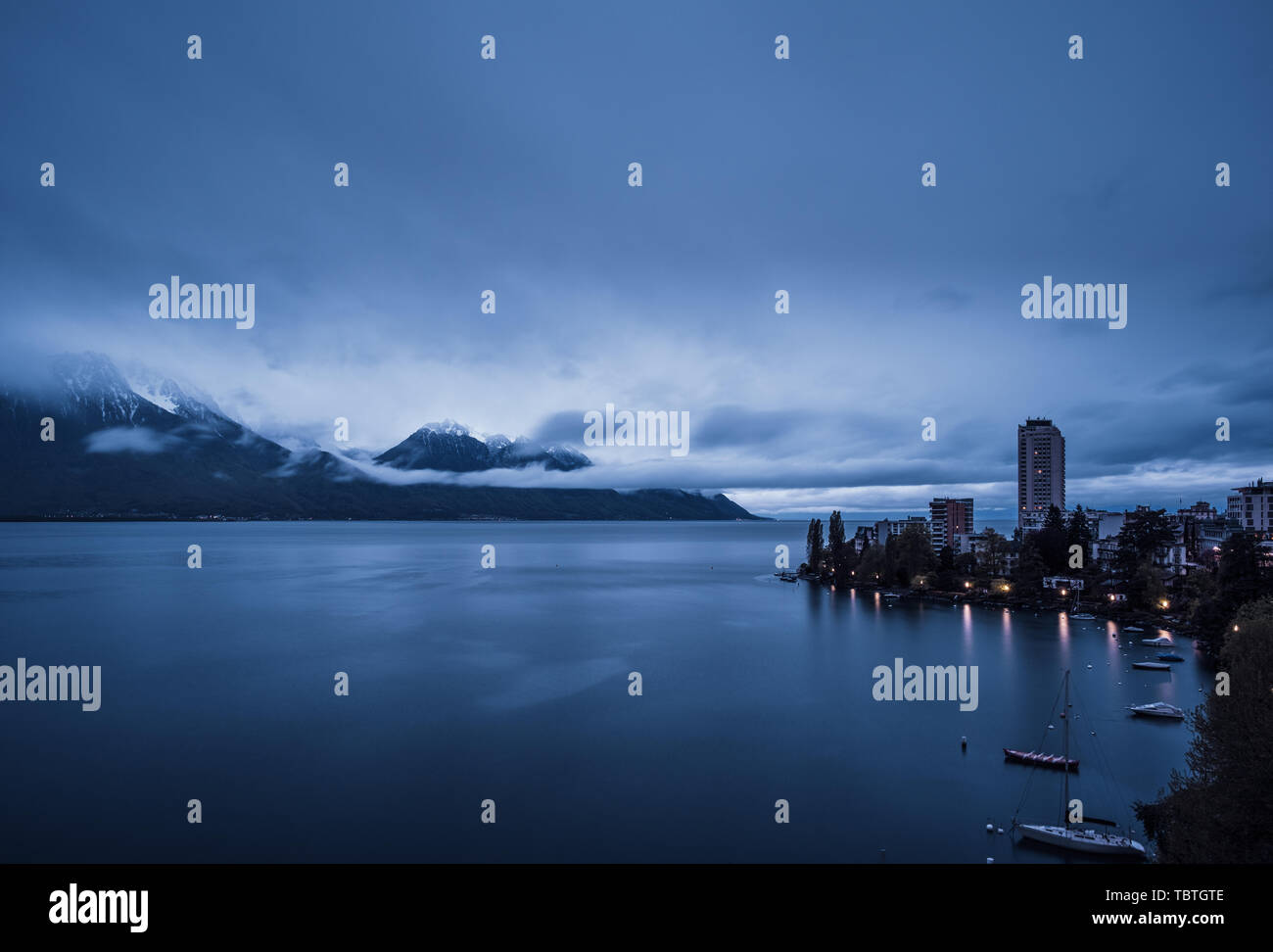 Tôt le matin, les nuages qui se forment sur des montagnes enneigées derrière le Lac Léman avec Laussane en premier plan Banque D'Images