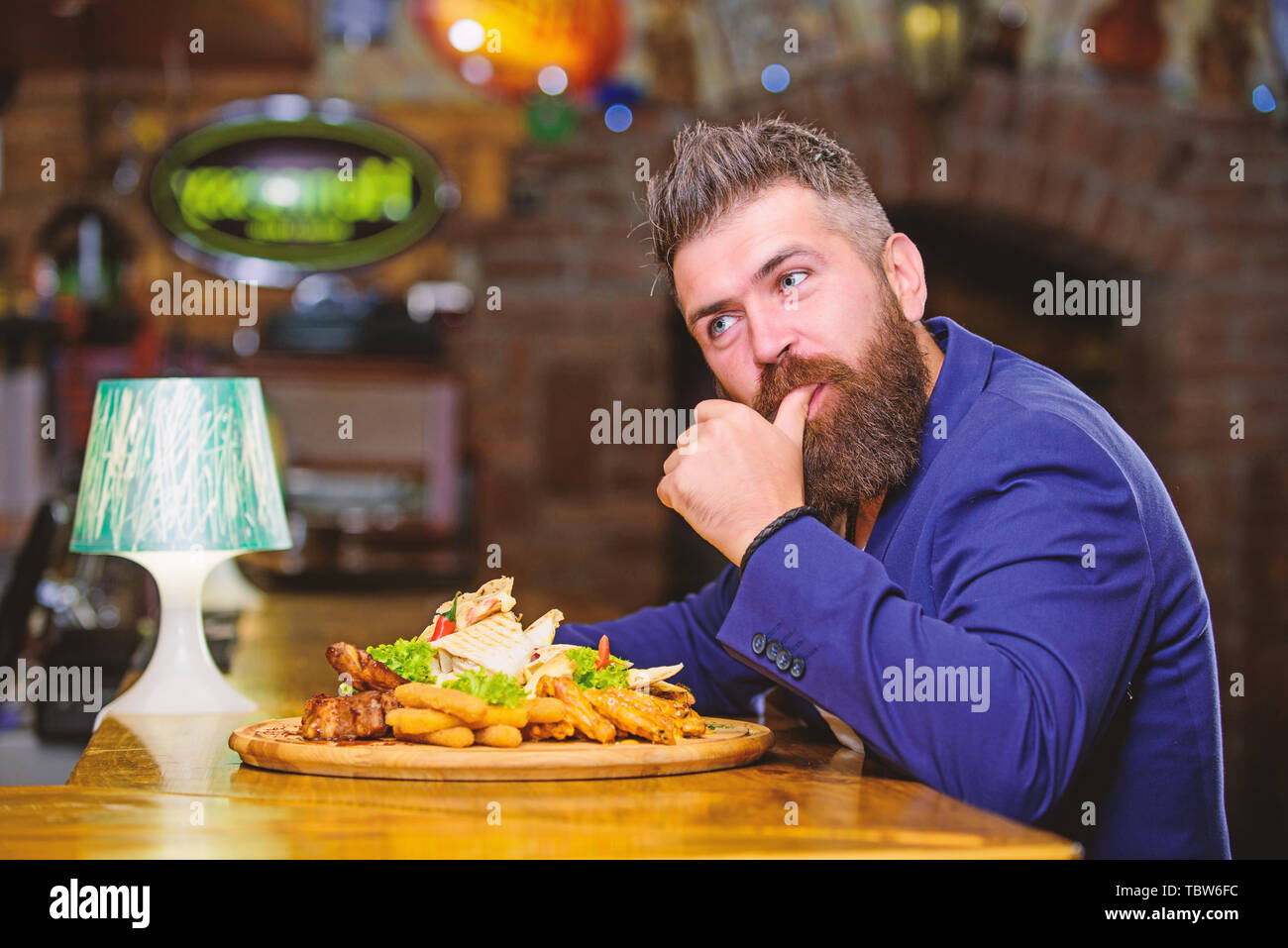 Hipster faim manger pub aliments frits. L'homme a reçu de pommes de terre frites repas avec les bâtonnets de poisson viande. Des calories. Profitez de repas. Tricher repas. Costume officiel Gestionnaire de siéger au comptoir du bar. Délicieux repas. Banque D'Images