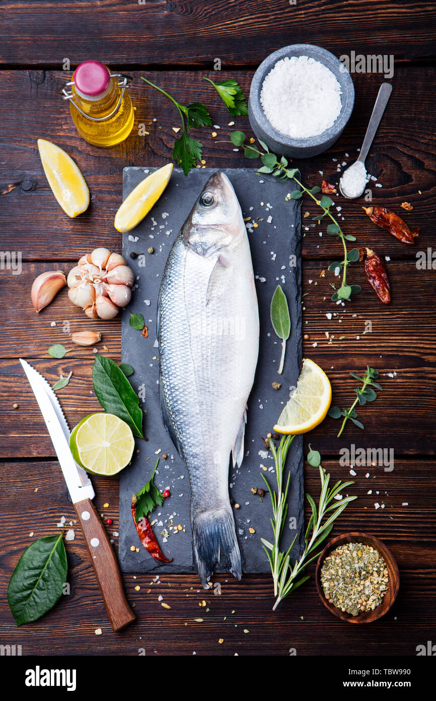 Le poisson cru, sea bass sur ardoise tableau noir. Ingrédients pour la cuisson, grill, la torréfaction. Vue d'en haut. Banque D'Images