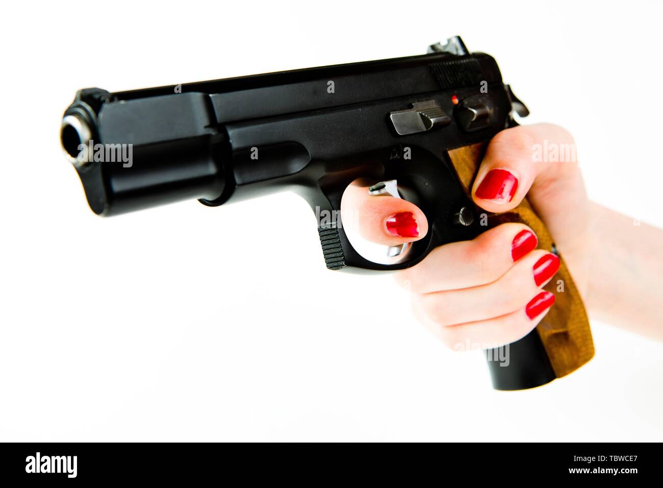 Big Black pistolet semi-automatique avec poignée en bois dans la main de petite femme avec manucure Banque D'Images