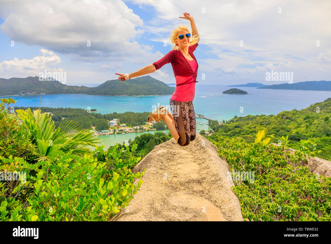 Praslin, Seychelles liberté femme sautant. Heureux joyeux cavalier touristiques à l'île de lookout après une randonnée à l'intérieur de la réserve de fond Ferdinand. Scenic top Banque D'Images