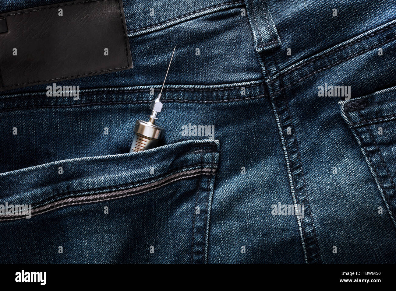 Seringue injecteur Vintage dans la poche arrière des jeans. Problème de dépendance de drogues et d'héroïne chez les jeunes. Banque D'Images