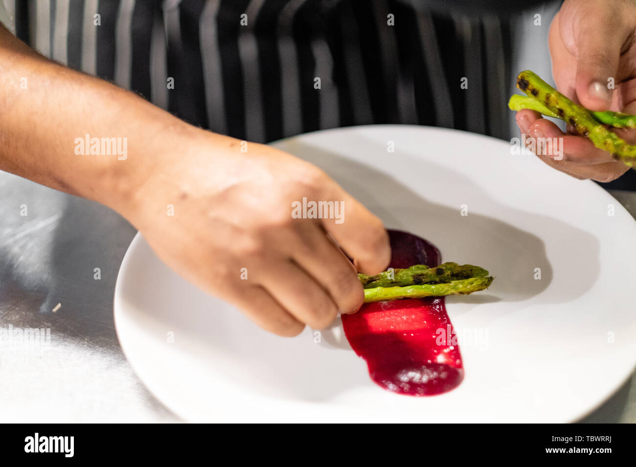 Close up of chef professionnel qualifiés mains sain et placage coloré nourriture d'asperges,sauce tomate betterave,dans une assiette blanche, la créativité dans un en Banque D'Images