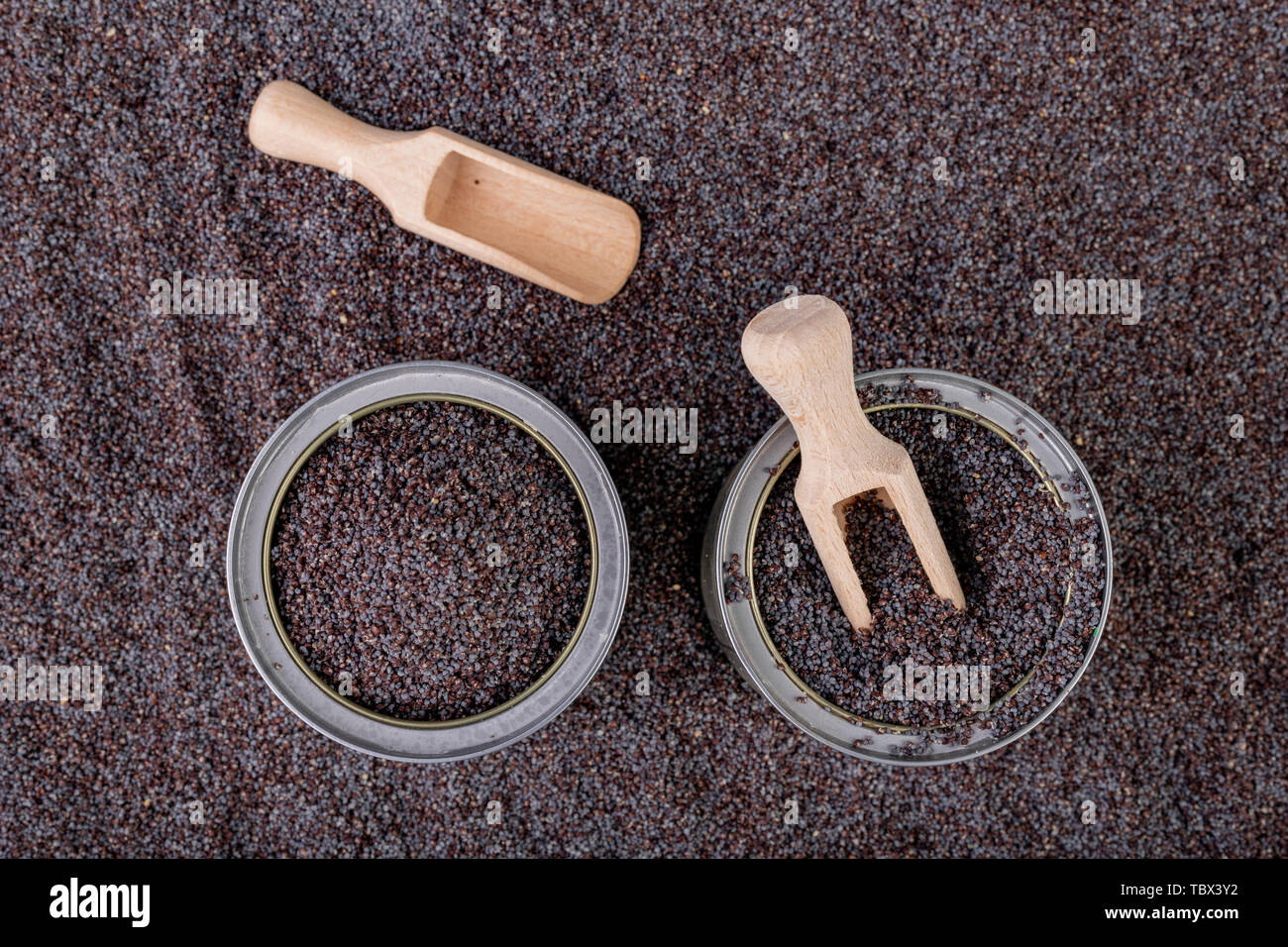 Un grain d'opium dans un peut sur une table de cuisine. Récupérer les graines de pavot et cuillère en bois sur une cuve de stockage. Fond sombre. Banque D'Images