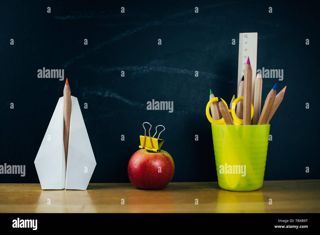 Avion en papier, crayons de couleur et de pomme fraîche sur tableau