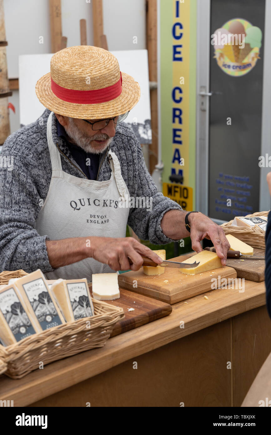 L'homme à chapeau de paille donne des échantillons de fromage de quicke au Devon County Show Banque D'Images