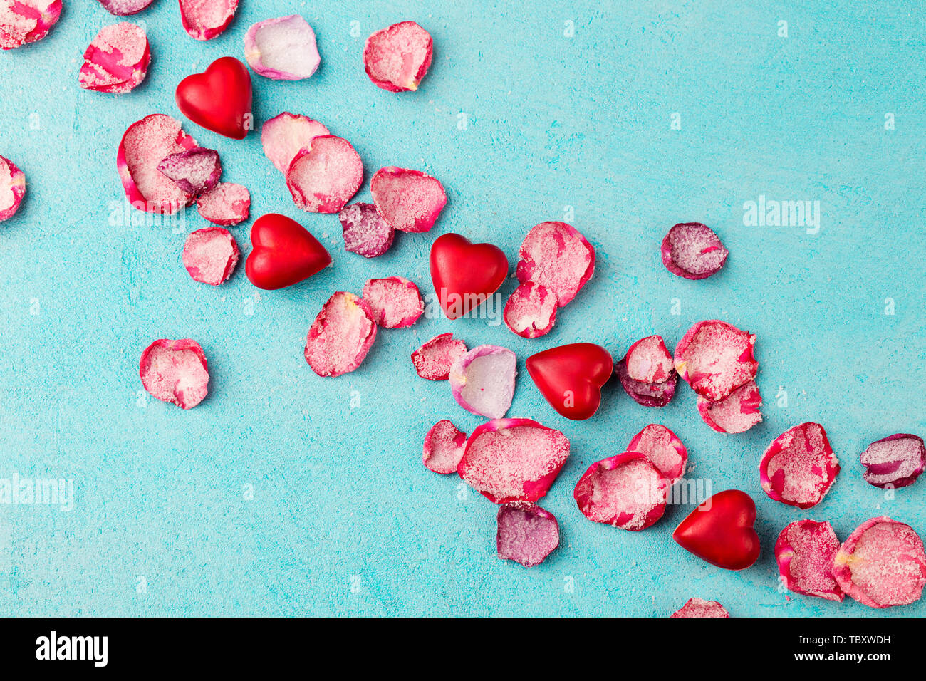 Coeur chocolat et bonbons en forme de lèvres rose avec pétales sucrés confits. Fond bleu. Vue d'en haut. Banque D'Images