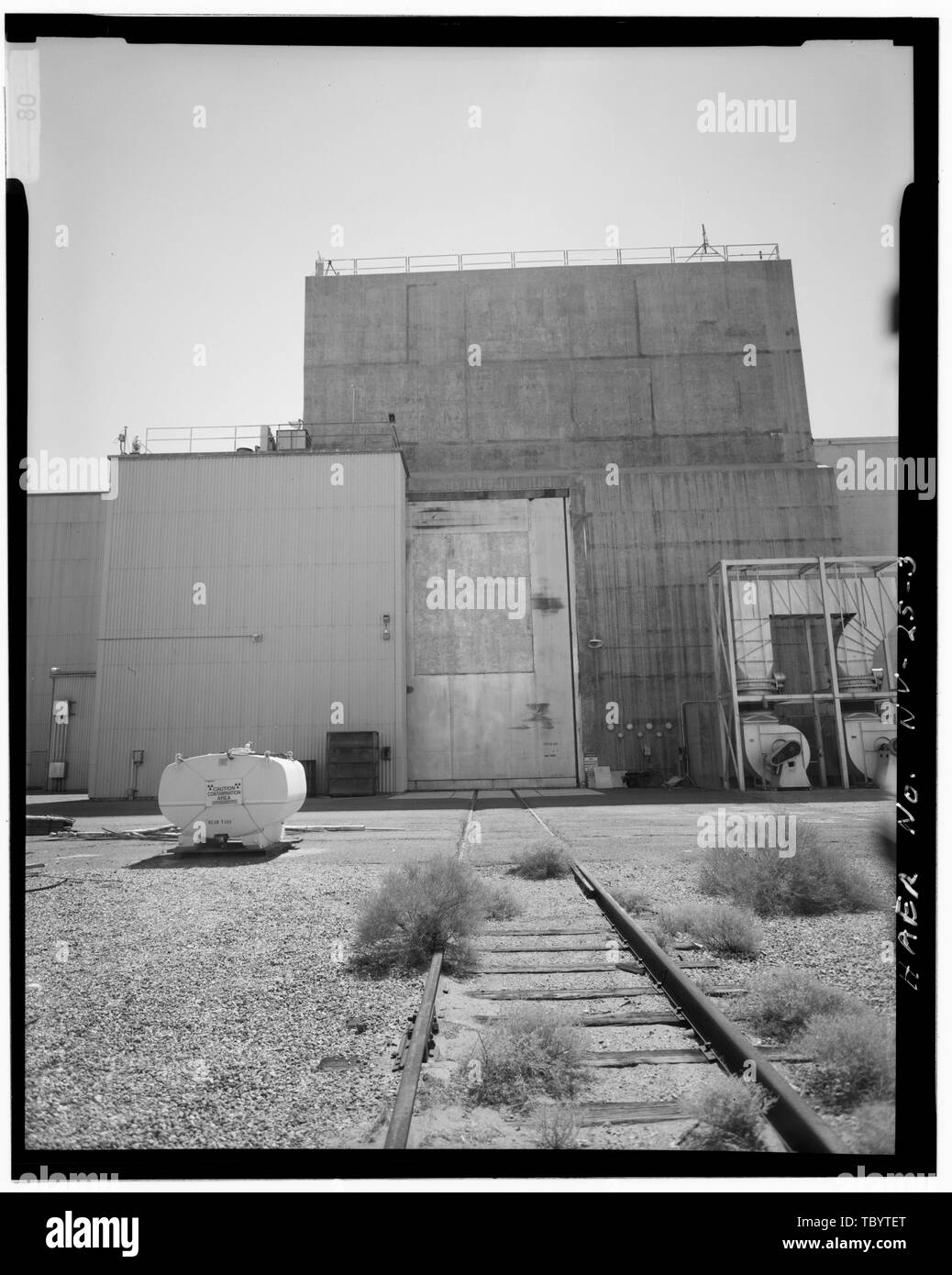 Élévation NORD DE LA BAIE CHAUDE, MONTRANT DES VOIES DE CHEMIN DE FER MENANT À LA PORTE D'ENTRÉE MASSIVE DE BÉTON STEELLINED. Une partie de la complexité d'un système de CVC est à l'ouest (droite) DE LA PORTE. Nevada Test Site, Maintenance moteur Facilité de montage et démontage, zone 25, Jackass Flats, Mercure, Nye Comté, NV Banque D'Images