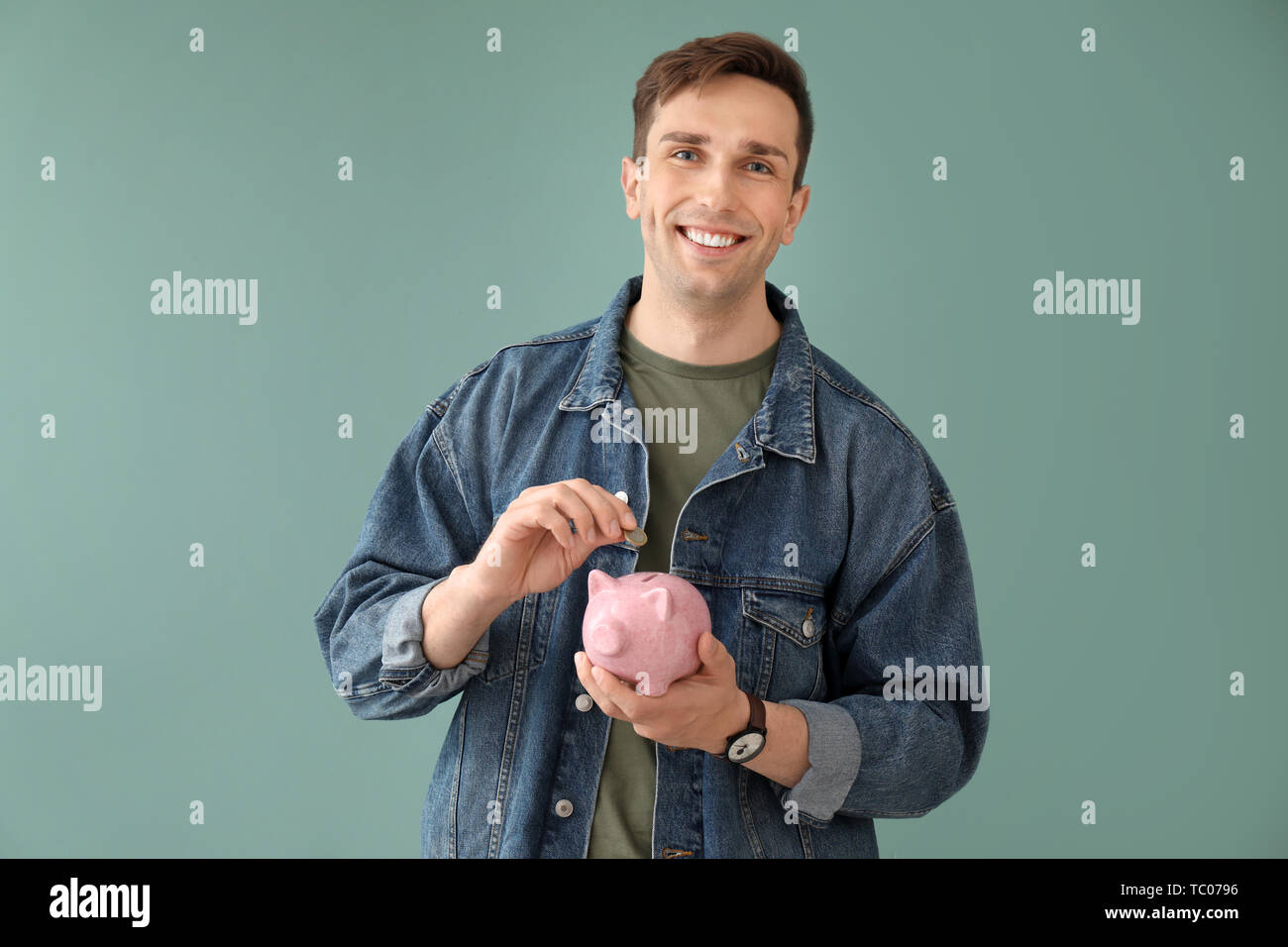 Jeune homme à la tirelire sur un fond de couleur Banque D'Images