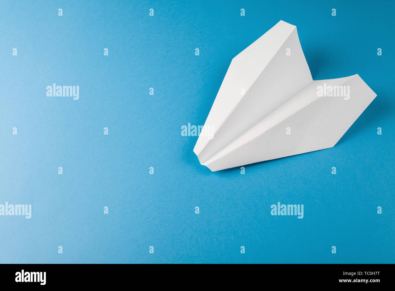Mise à plat de l'avion en papier blanc sur fond de couleur bleu Banque D'Images