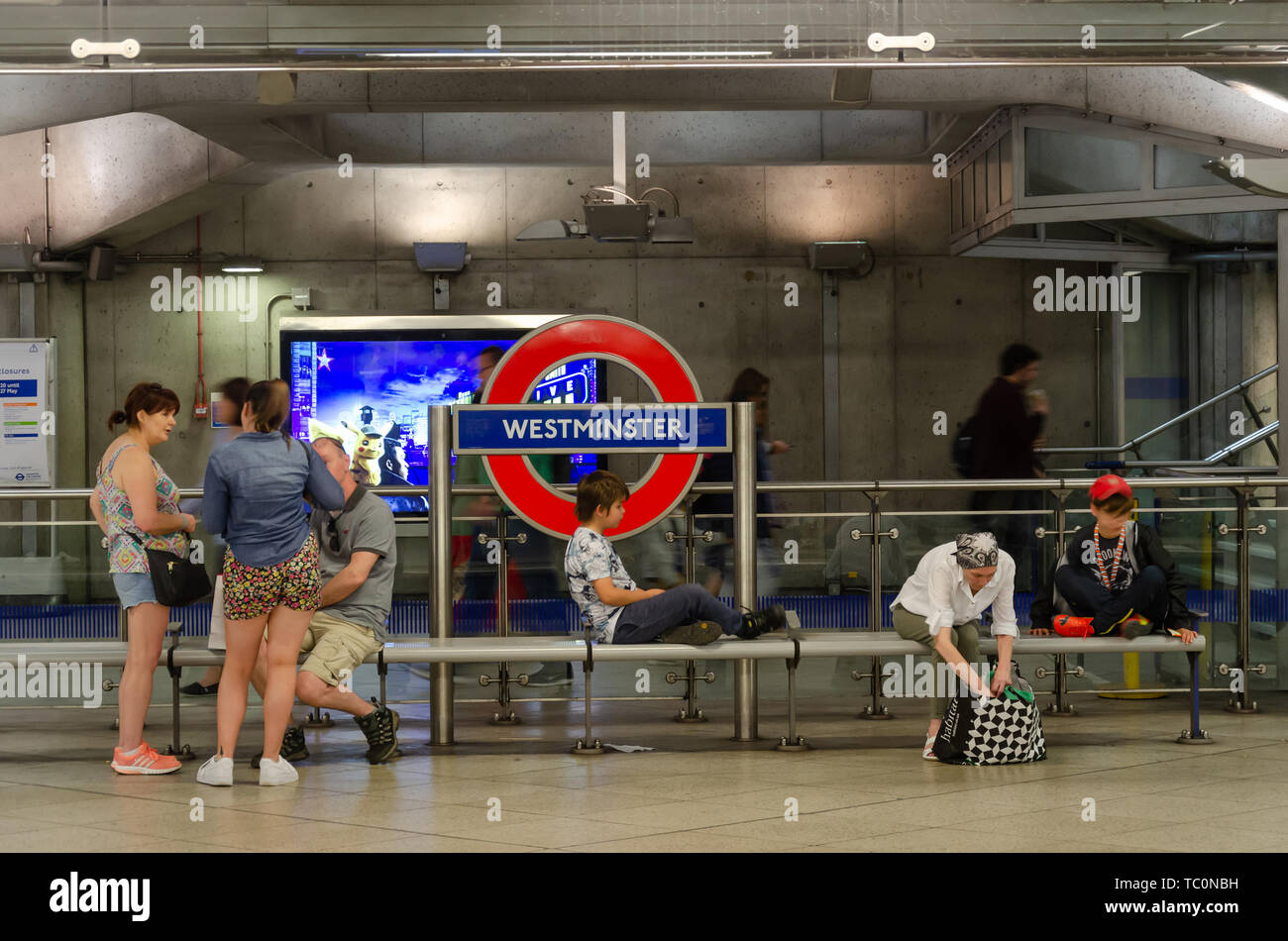 Les gens s'asseoir sur un banc sur la plate-forme à la station de métro Westminster Banque D'Images