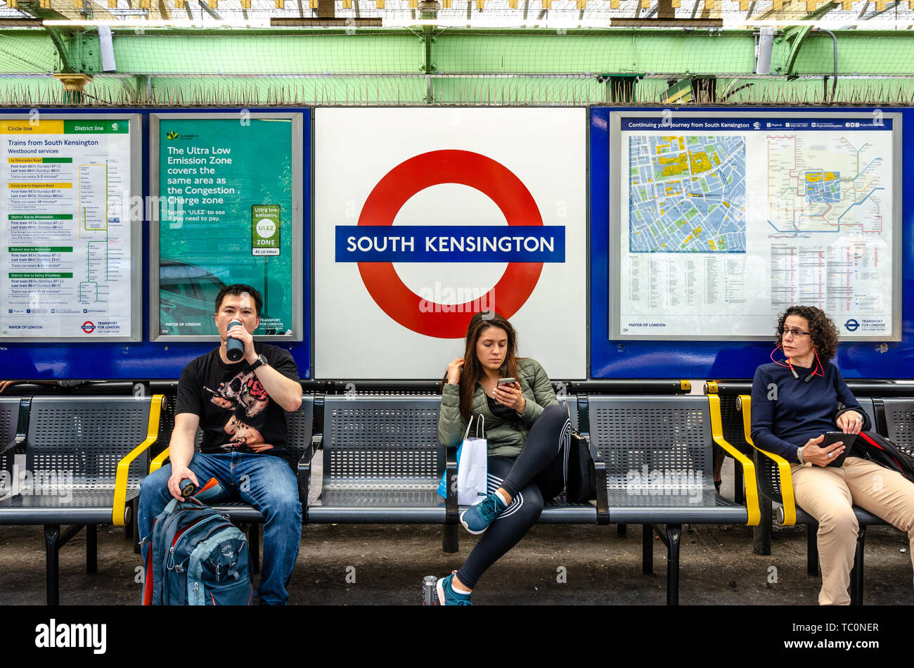 Les gens s'asseoir sur un banc sur la plate-forme à la station de métro South Kensington. Banque D'Images