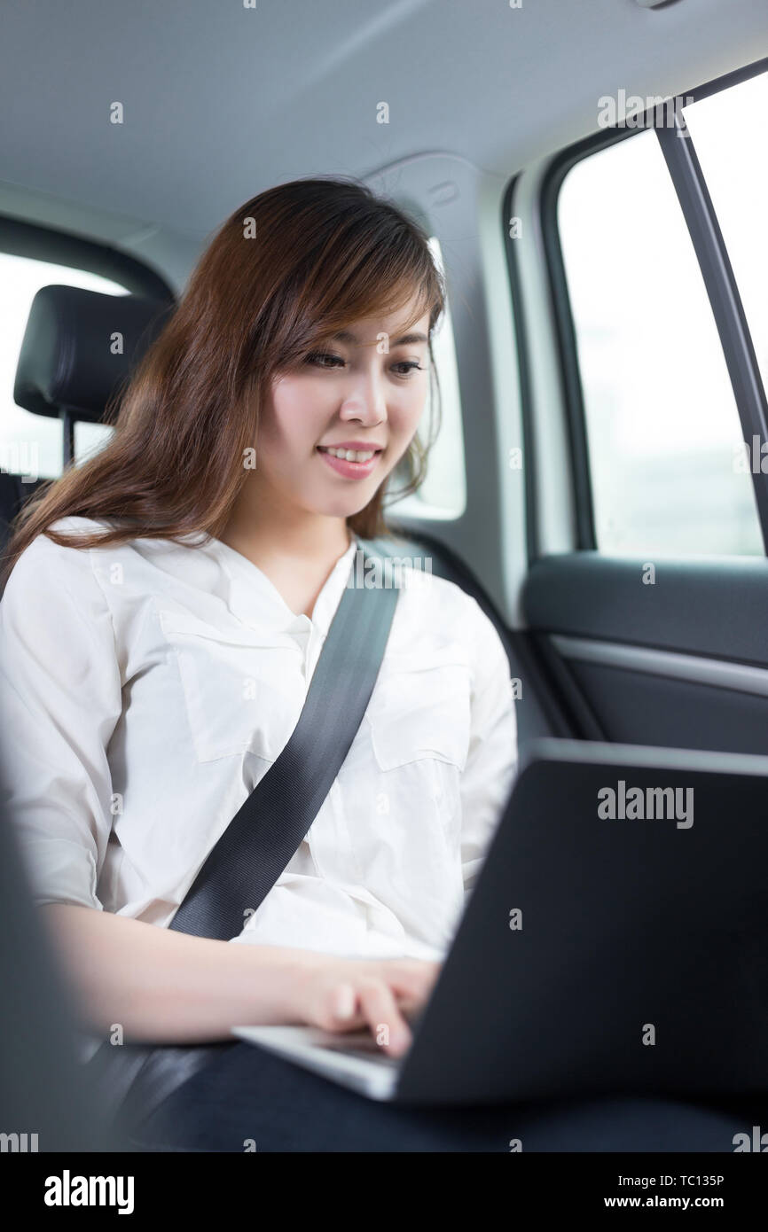 Belle asiatique young woman using laptop in car Banque D'Images
