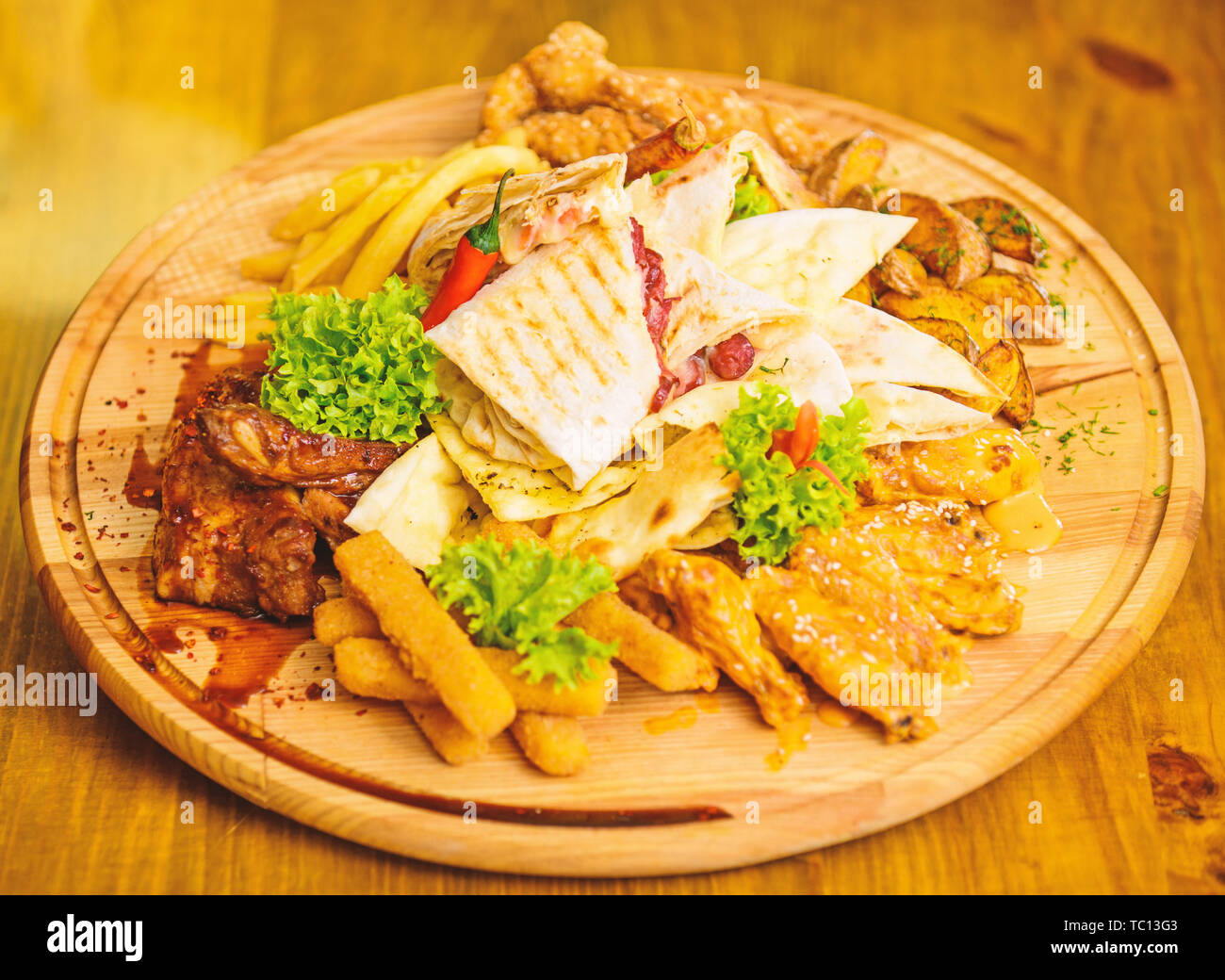 Snack de viande pour le groupe d'amis. De délicieux en-cas savoureux. Les repas au restaurant. Snack pour la bière. Planche de bois frites et bâtonnets de poisson viande burrito steak servi avec une salade. Profitez de votre repas. Menu snack-bar. Banque D'Images