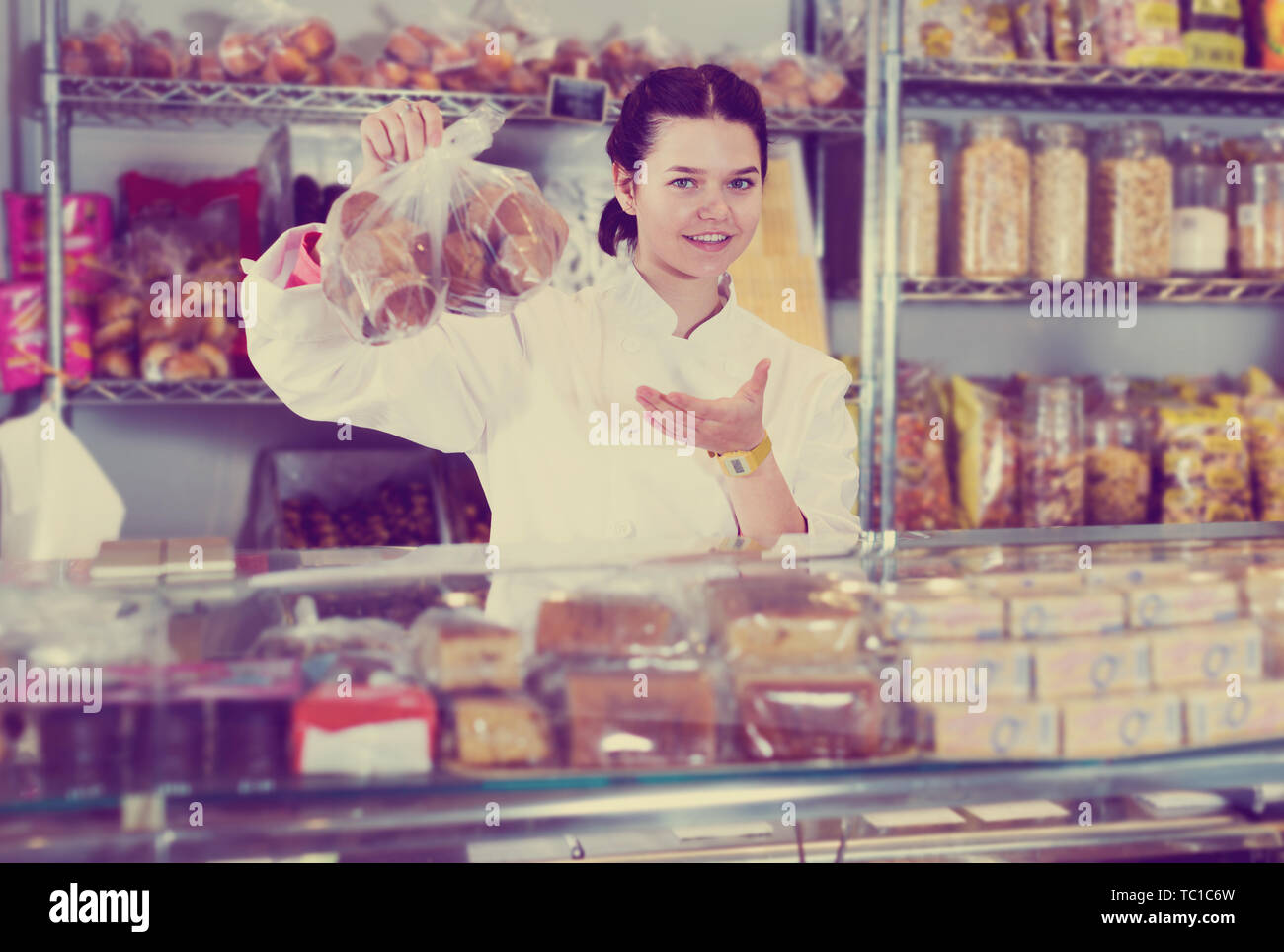 Jeune vendeur positive en uniforme blanc avec des cookies à afficher Banque D'Images