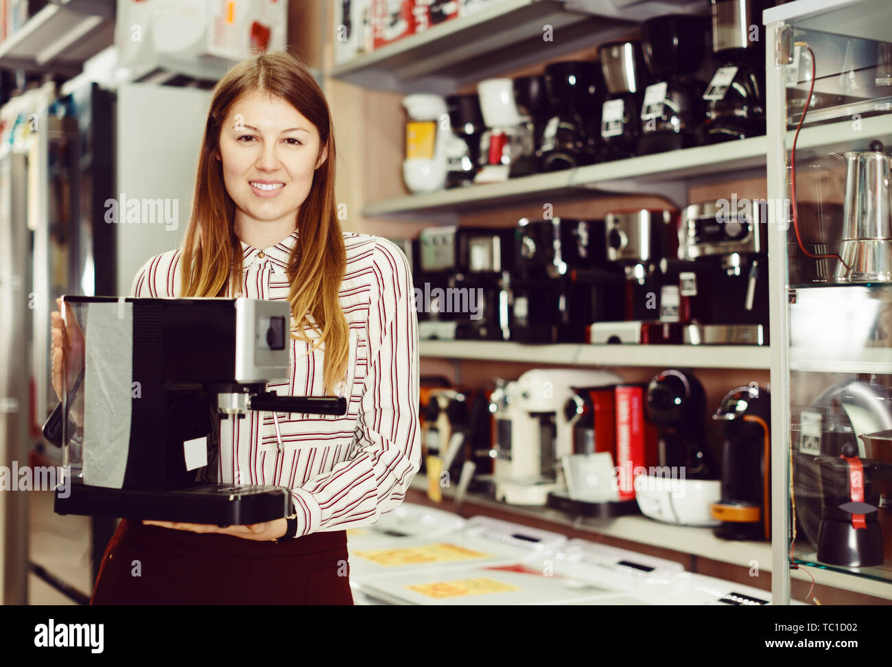 Jeune vendeuse suggérant une machine à café dans la boutique Banque D'Images