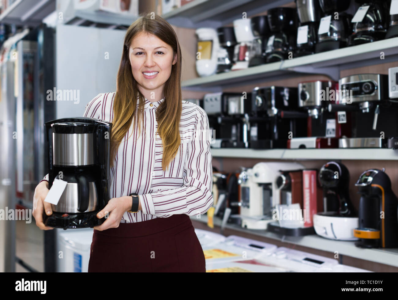 Smiling saleswoman suggérant infuseur à café dans le magasin d'appareils de cuisine Banque D'Images