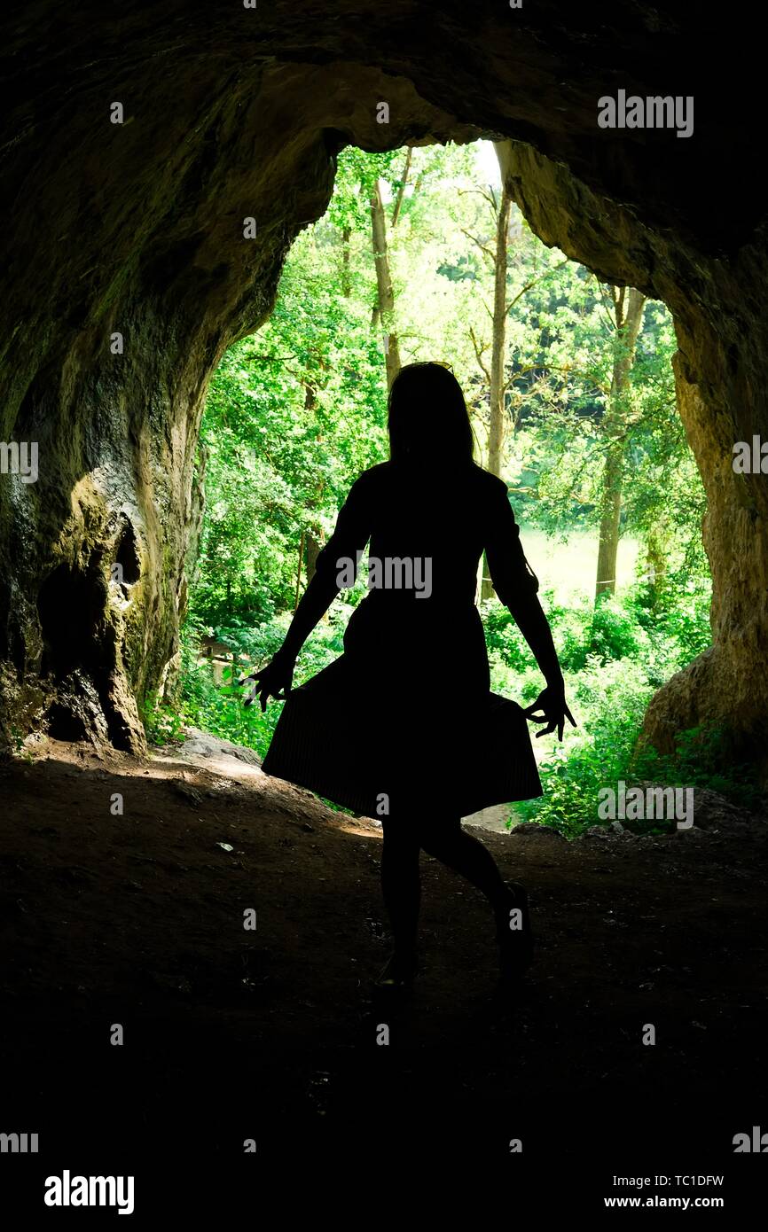La silhouette de femme à l'entrée de grotte naturelle dans la forêt, accueil des peuples anciens Banque D'Images