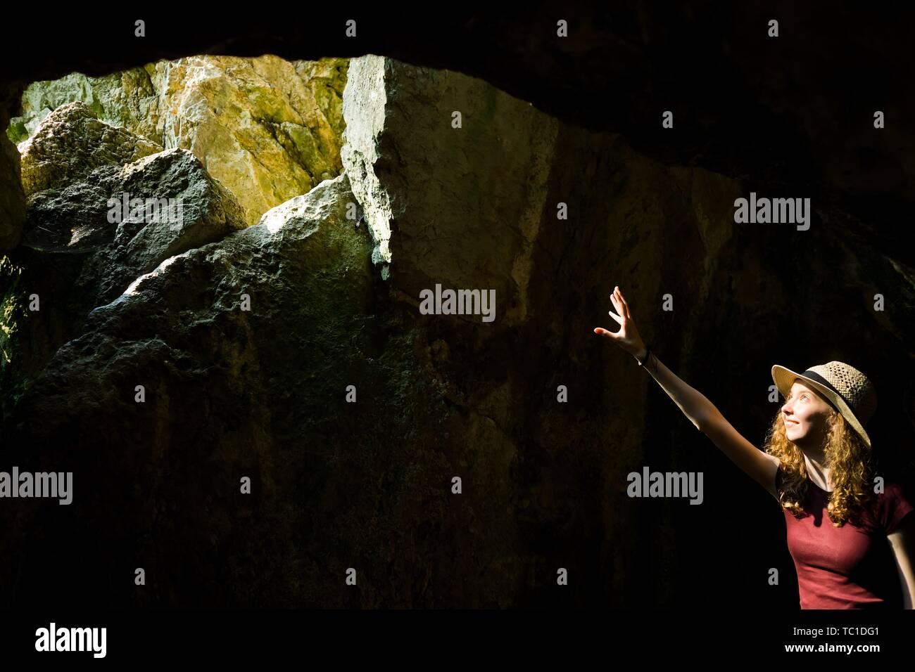 Un jeune explorateur girl à hat pointant et trou dans l'ancienne cave où le soleil va à l'intérieur Banque D'Images