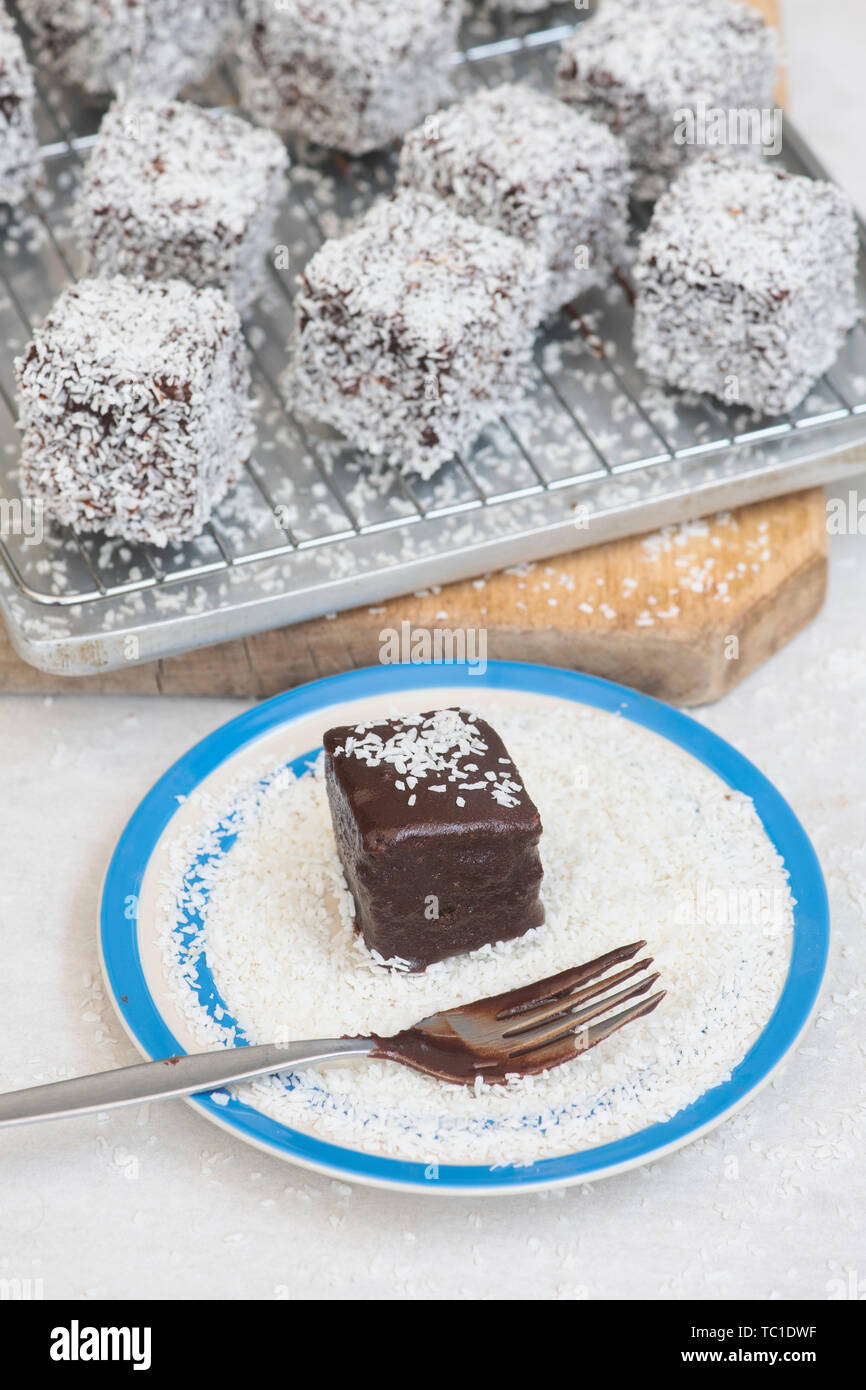 Des gâteaux de Lamington. Gâteau d'Australie. Gâteau éponge coupé en cubes enrobés d'une couche de sauce au chocolat et roulé dans la noix de coco desséchée Banque D'Images