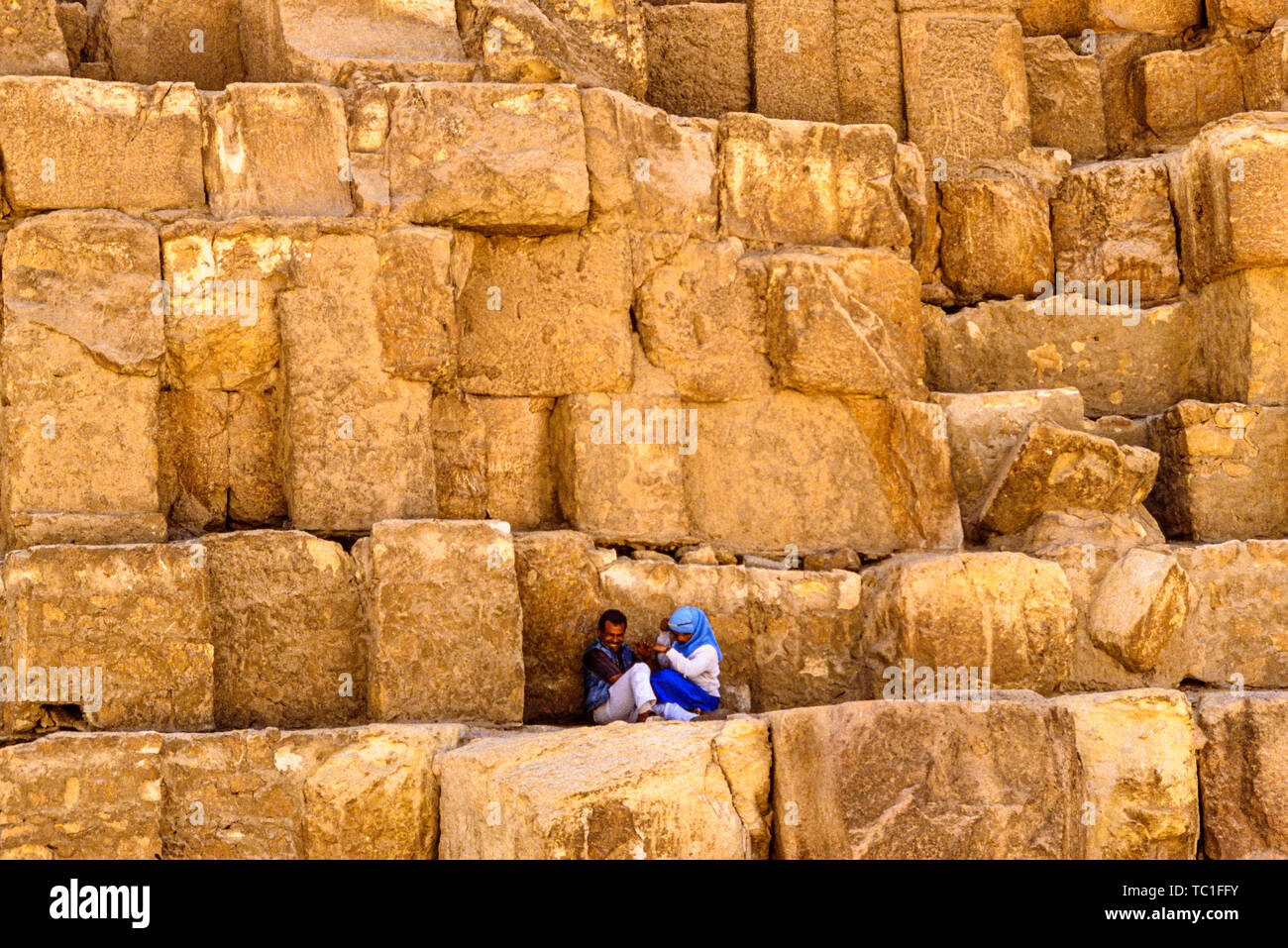 Photo : © Simon Grosset. La pyramide de Gizeh, Nécropole de Gizeh ou complexe, près du Caire, Égypte. Un couple reste à l'ombre sur les blocs de la Grande Pyramide Banque D'Images