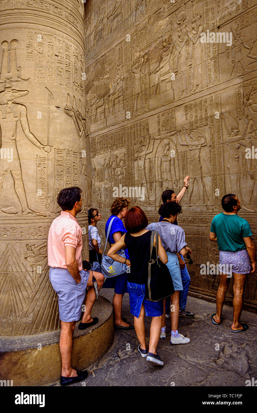 Egypte : les touristes étant illustré d'hiéroglyphes et bas-relief décoration dans un temple sur le Nil. Photo : © Simon Grosset. Archive : image numérisé à partir d'un ou Banque D'Images