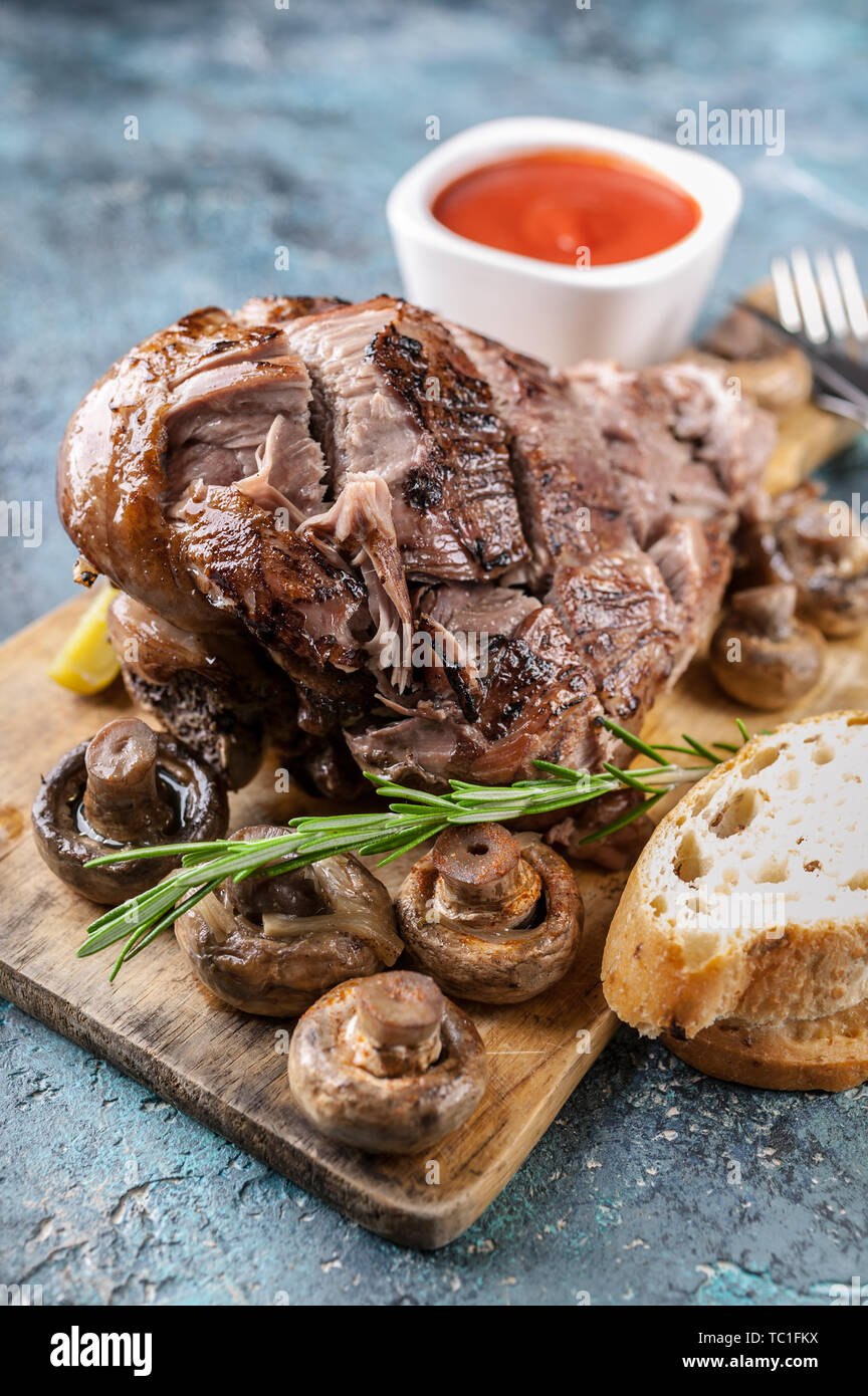 Close-up ram grillés jambe avec champignons, légumes, épices sur une planche à découper. La viande halal et de l'alimentation Banque D'Images