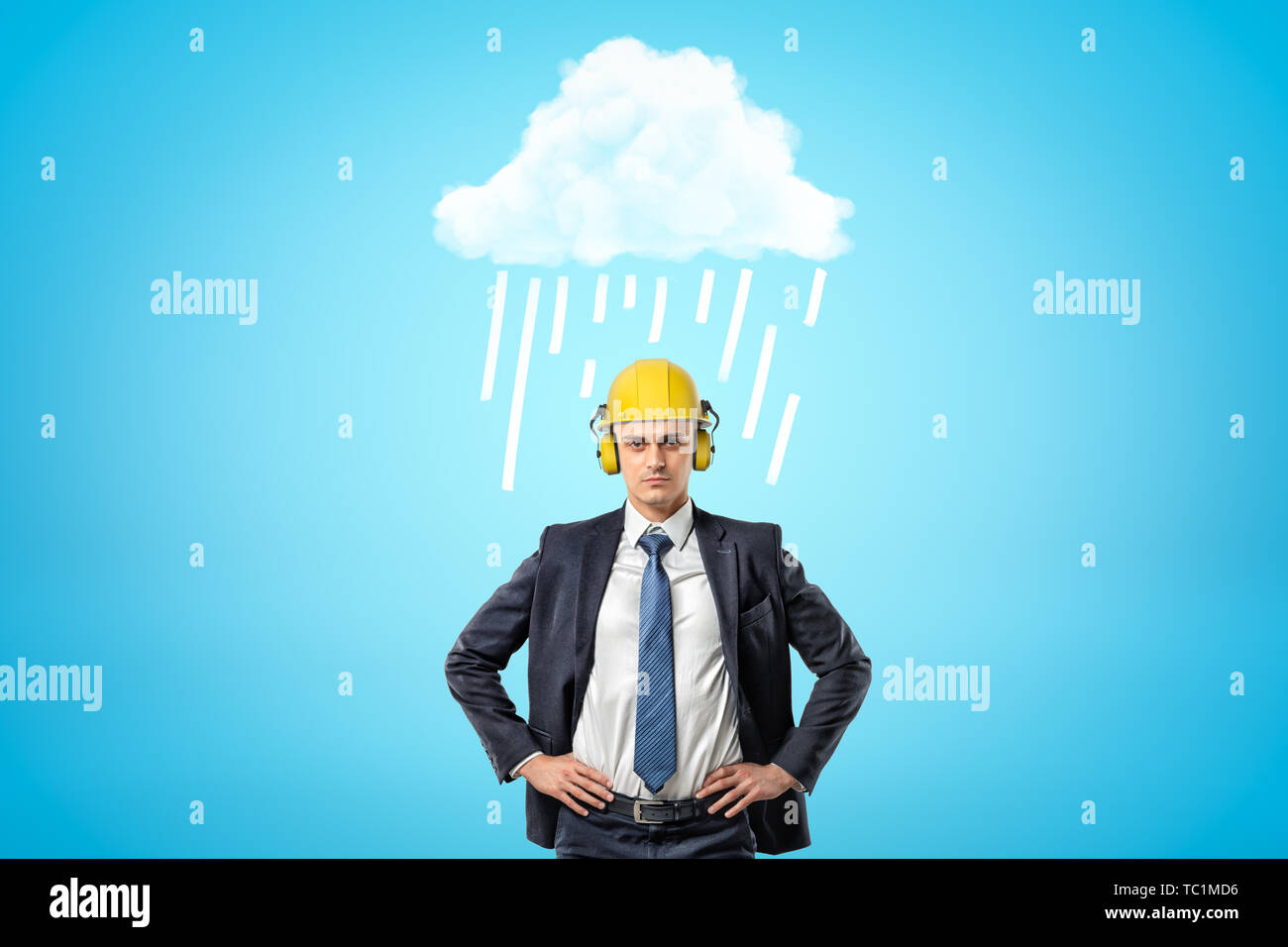 Avant petit image de businessman en jaune casque avec protège-oreilles, debout avec les mains sur les hanches sous la pluie blanc nuage. Banque D'Images