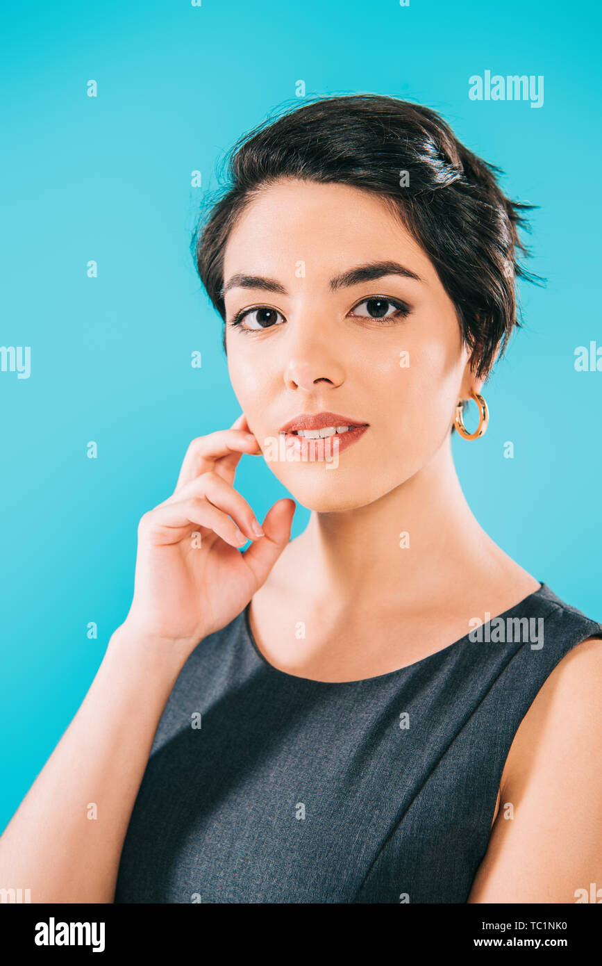 Portrait of beautiful mixed race woman looking at camera tout en tenant la main près isolé face sur bleu Banque D'Images