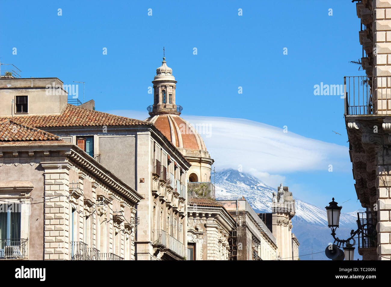 Coupole de la Cathédrale de Sainte Agathe à Catane, Sicile, Italie entouré par d'autres bâtiments historiques dans le centre-ville. Dans l'arrière-plan célèbre volcan Etna avec de la neige sur le sommet. Banque D'Images