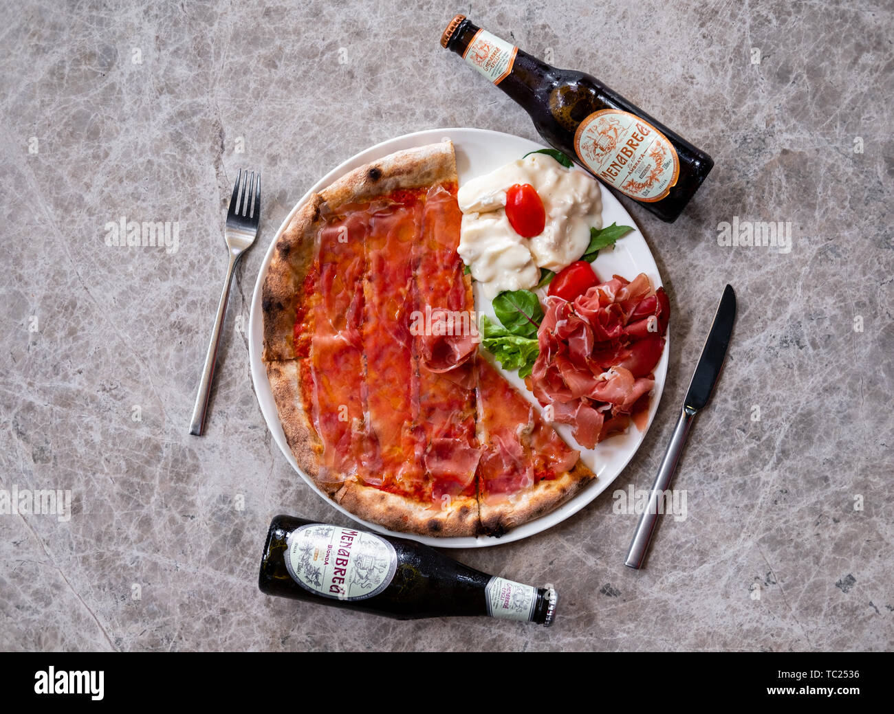 Gros plan d'une pizza jambon fumé en tranches de parme, chef de pizza italienne fine cuisine gastronomique d'un éclairage naturel de charcuterie assiette de fromage gorgonzola, bois de la bière Banque D'Images