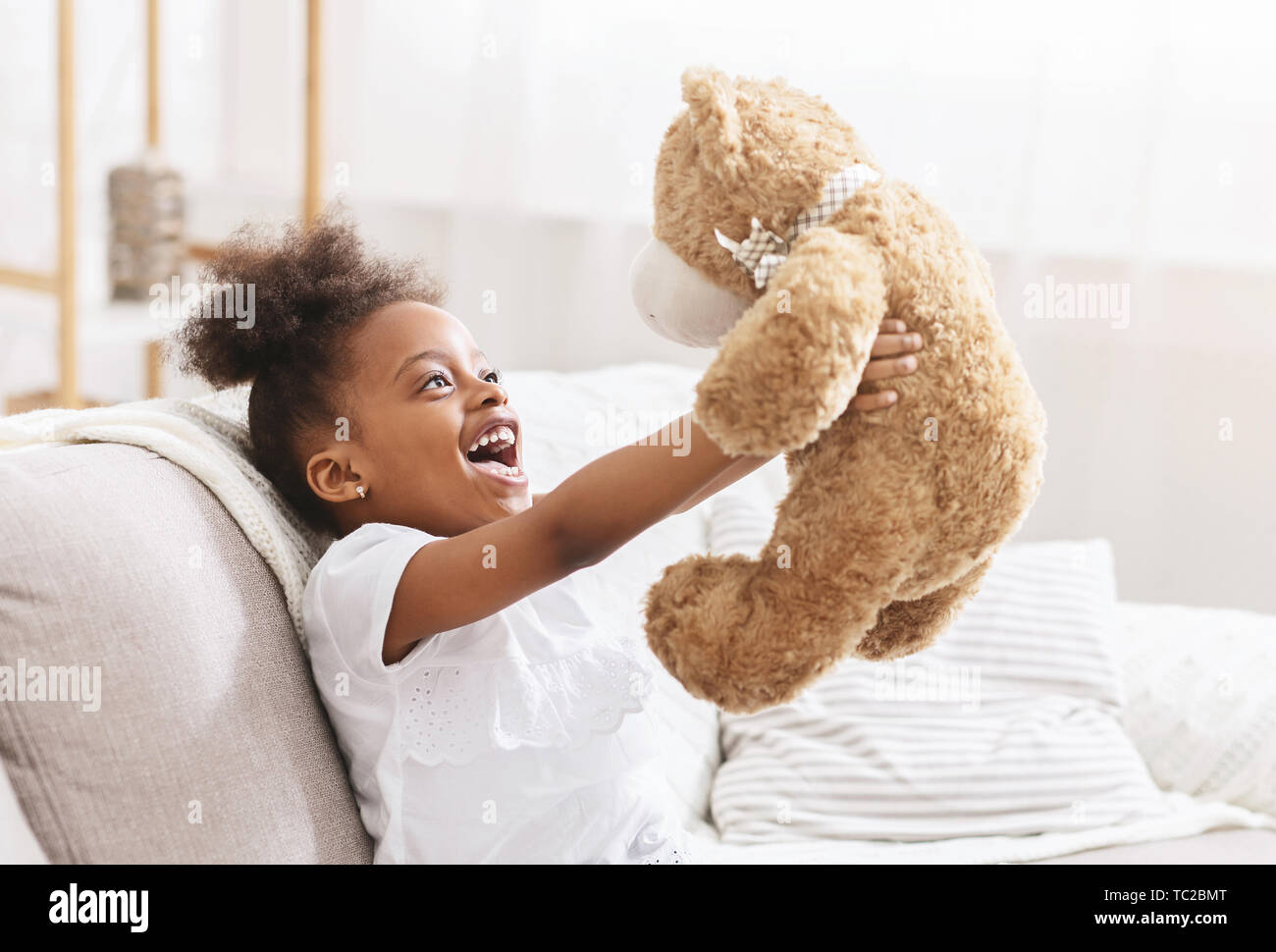 Cute african american child hugging teddy bear and smiling Banque D'Images