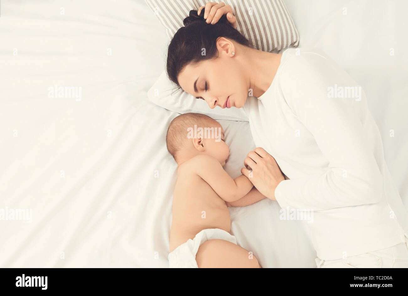 Jeune mère et son cute baby sleeping in bed Banque D'Images