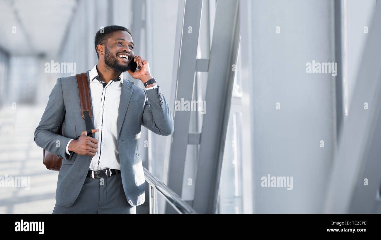 African Businessman Walking à l'intérieur de l'aéroport et parlant au téléphone Banque D'Images