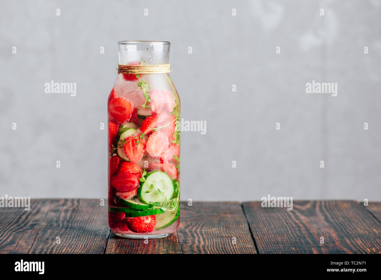 Bouteille de l'eau infusée avec des fraises fraîches, tranches de concombre et les ressorts de thym. Copier l'espace. Banque D'Images