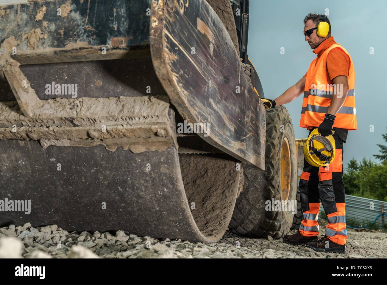 Rouleau d'exploitation. Young Construction Worker et lourds de construction de routes. Banque D'Images