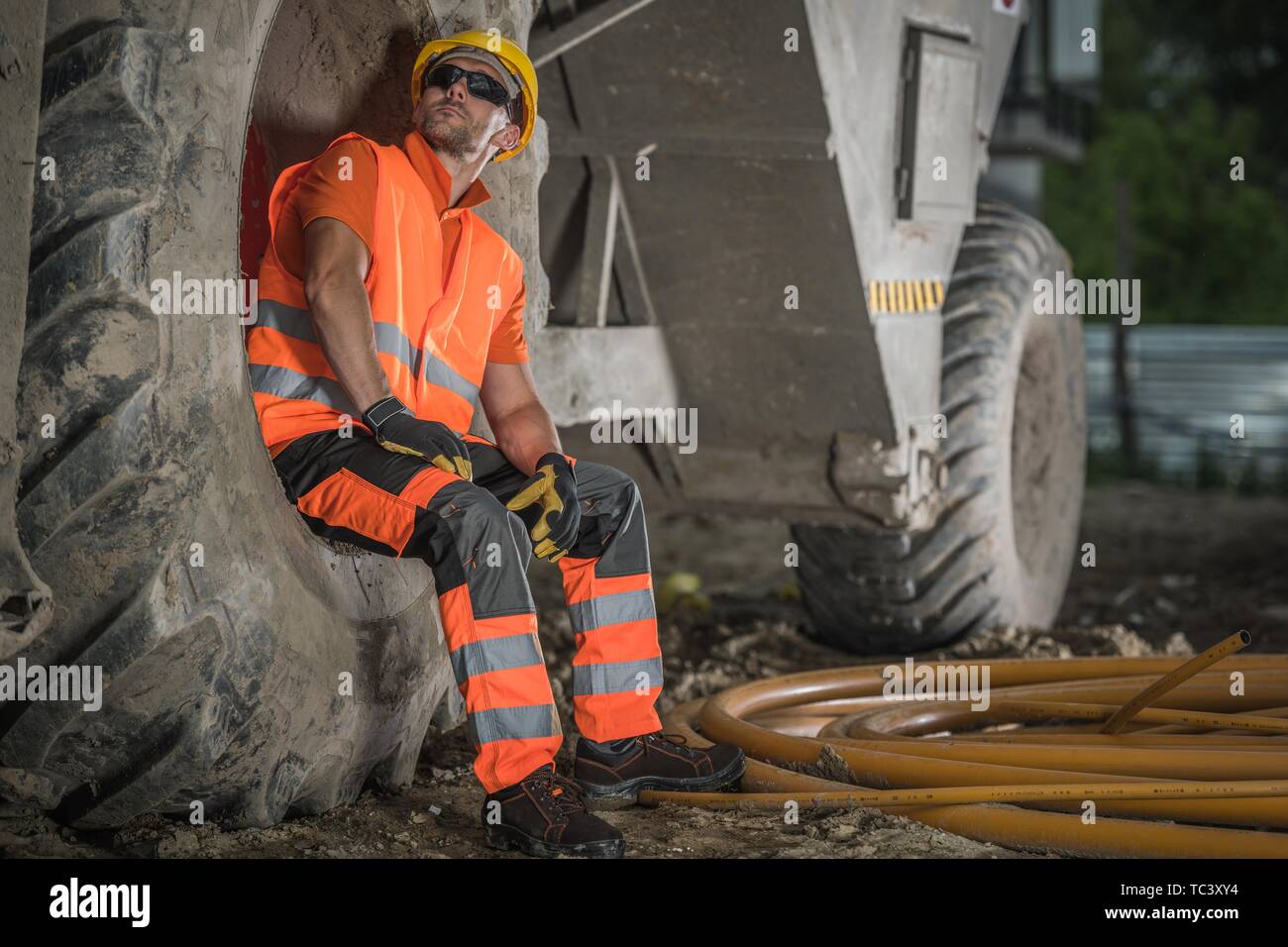 Travailleur de la construction de la route du Caucase dans la trentaine de prendre courte pause et reposant à l'intérieur de l'équipement lourd volant. Banque D'Images