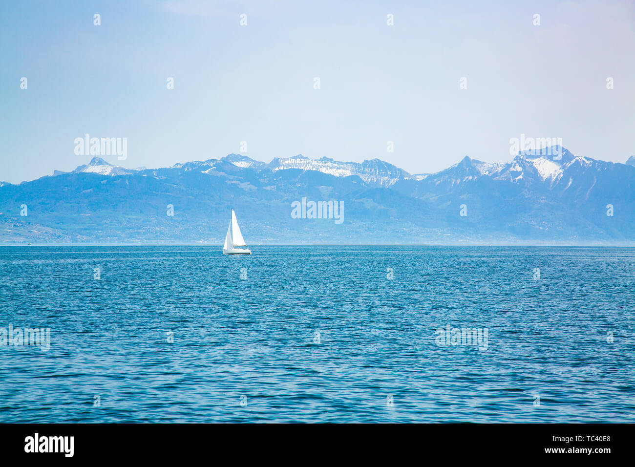 Seul Bateau à voile sur le Lac Léman et les montagnes en arrière-plan Banque D'Images