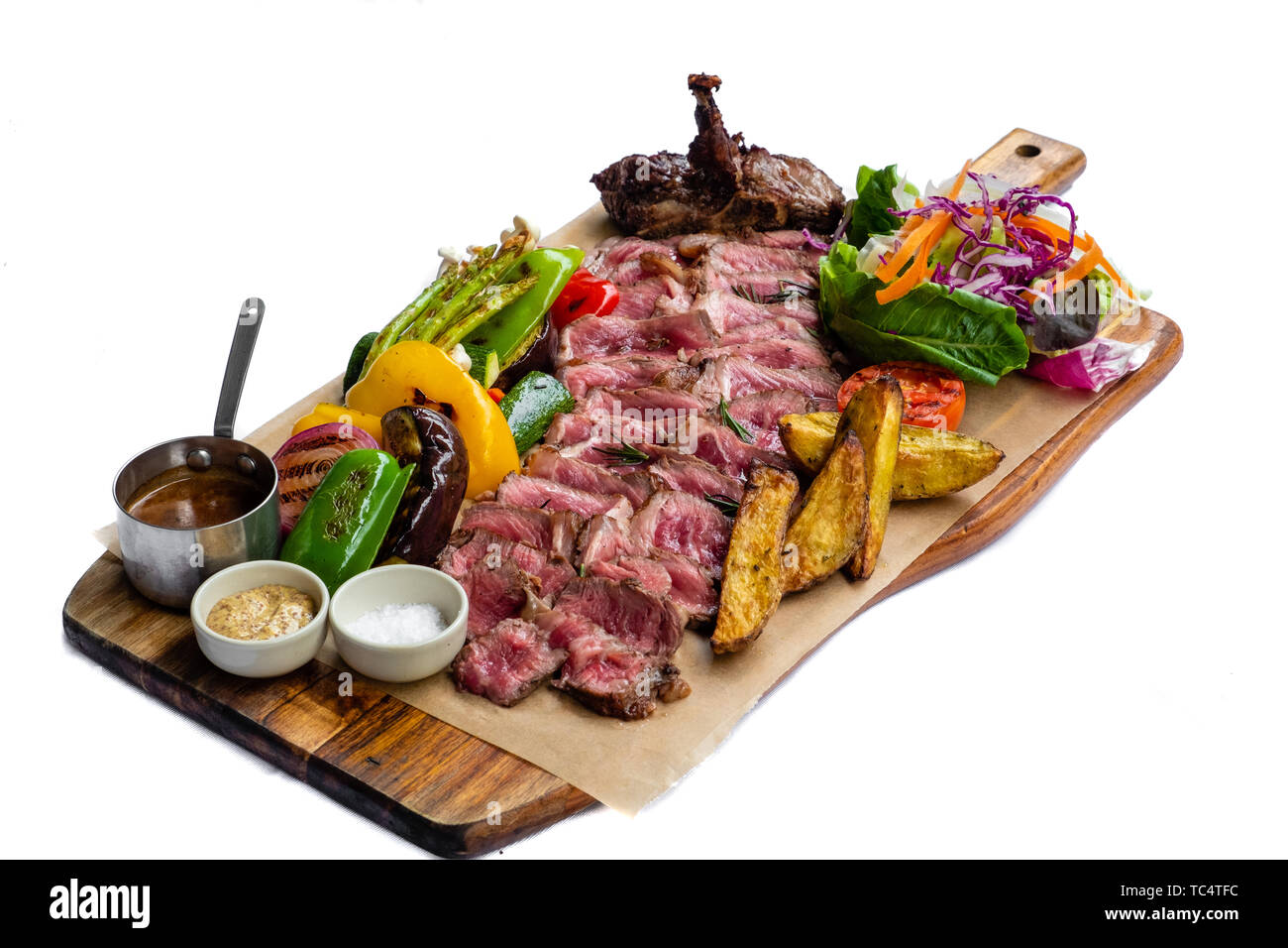 Close up de tranches de T bone steak fiorentina tagliata di manzo rôti aux légumes grillés salade de pommes de terre barbecue mélange frais sauce moutarde Sel de mer boa en bois Banque D'Images
