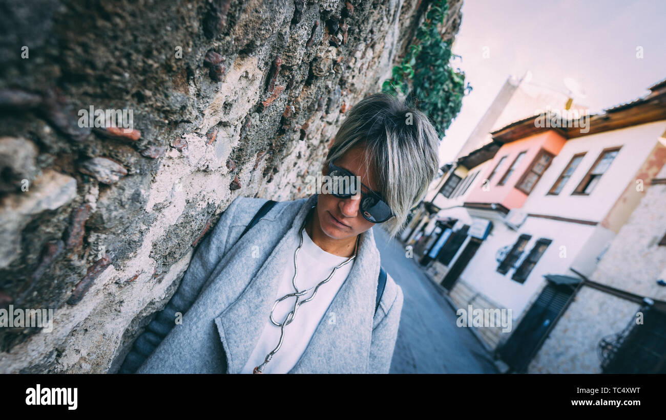 Jeune femme à la mode dans les rues d'Antalya. Belle blonde femme adulte debout contre le mur. Banque D'Images