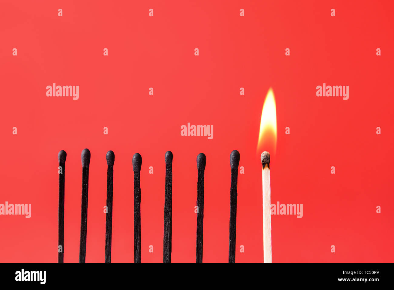 Un match brûlant parmi celles incendiées sur un fond de couleur. Concept de l'unicité Banque D'Images