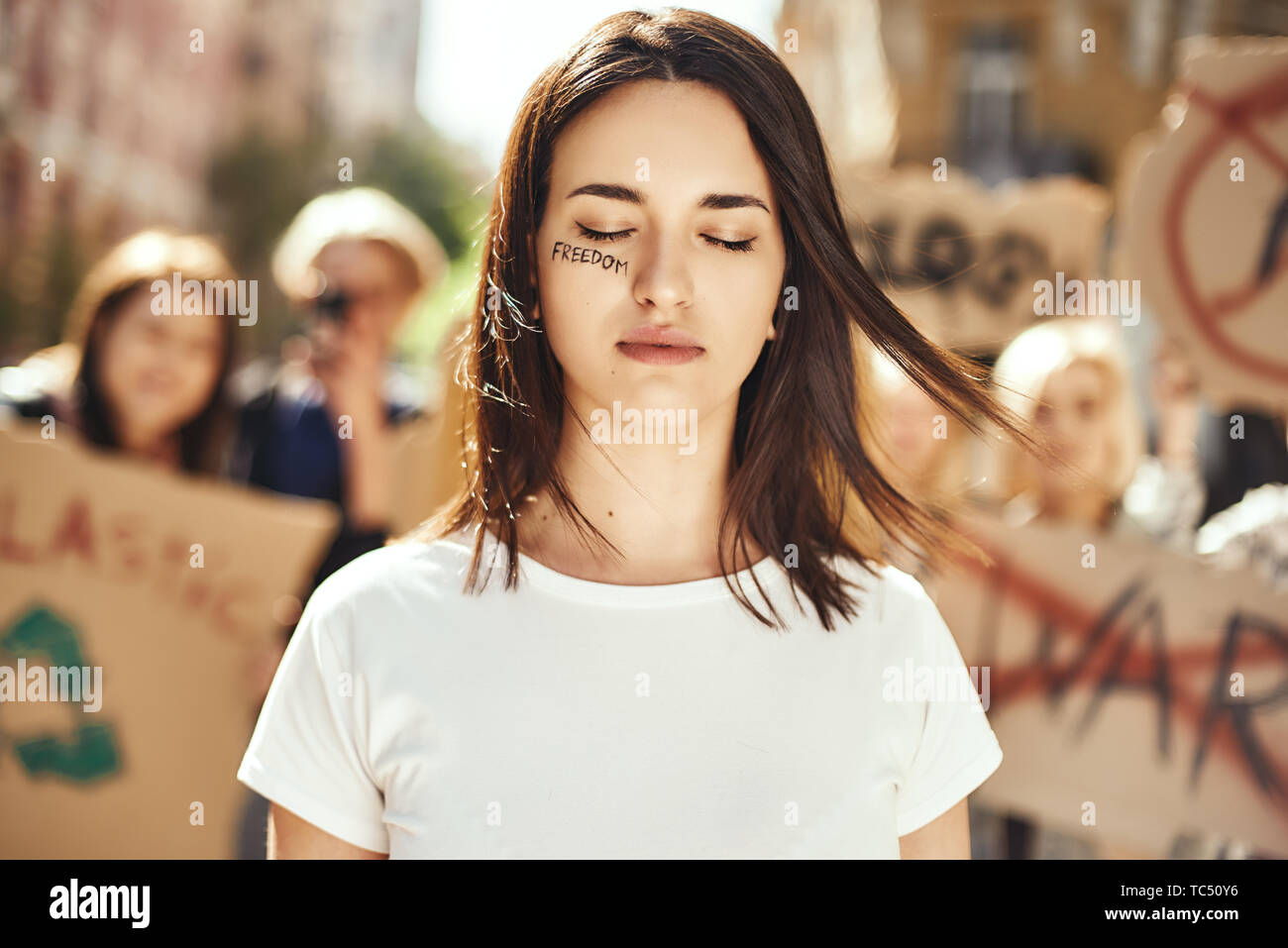 Changer le monde. Jeune et brave femme avec mot liberté écrit sur son visage aux yeux clos et debout autour de militantes sur la route au cours de protestation. Les droits des femmes. Les droits de l'homme. L'autonomisation des femmes Banque D'Images